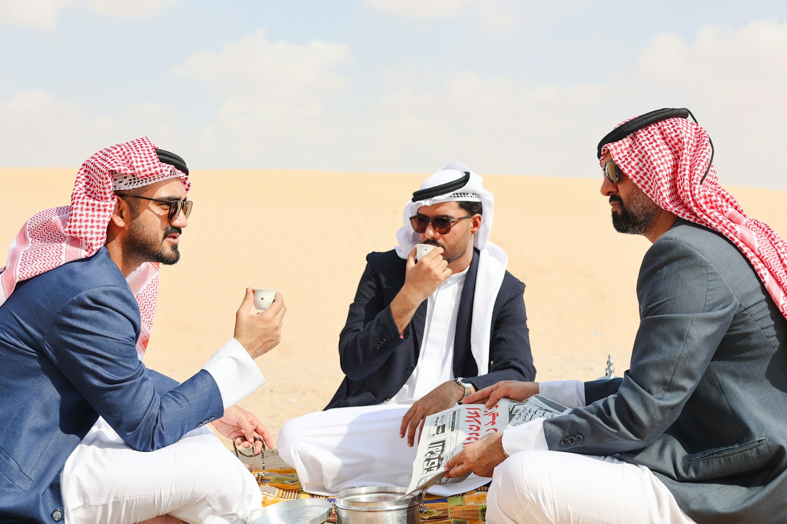 رجال بالشماغ يتحاورون في جلسة على الرمل